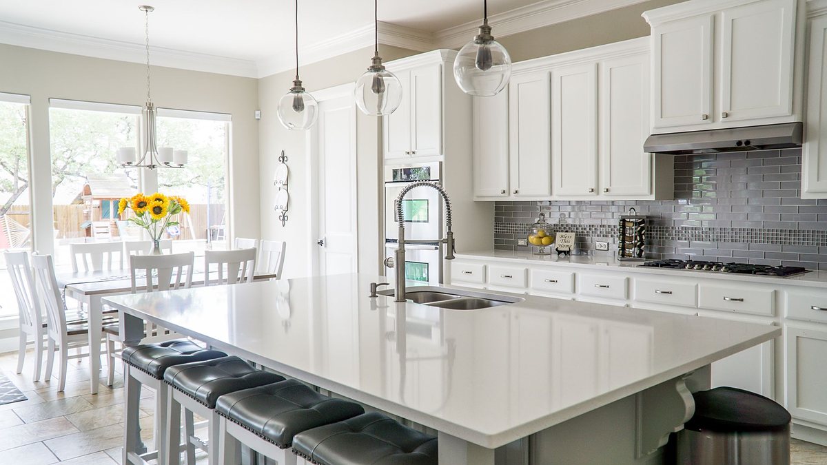 Spacious modern kitchen with white cabinets, an island and a dining area in natural light