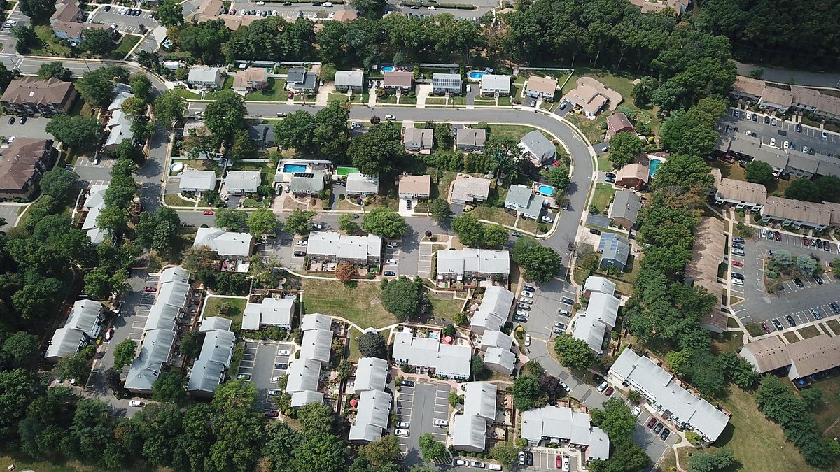 Drone view of a suburban residential area with houses and tree-lined streets