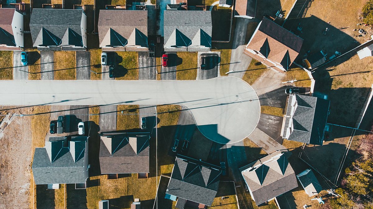 Aerial view of a residential cul-de-sac with neatly aligned houses, driveways and yards on a sunny day