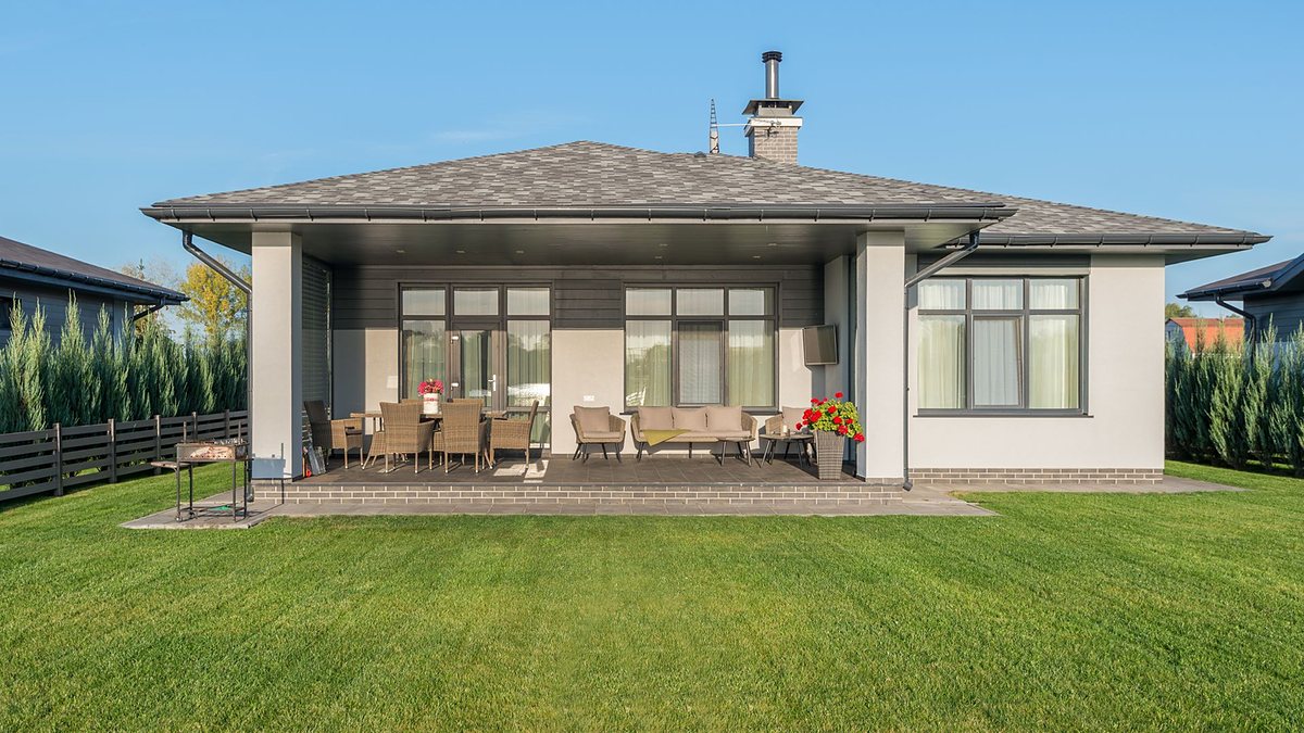Contemporary house exterior with a large backyard patio and manicured green lawn