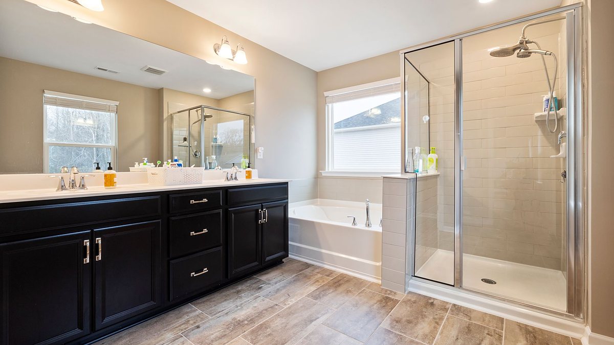 Spacious bathroom with a double vanity, bathtub and glass-enclosed shower with natural light
