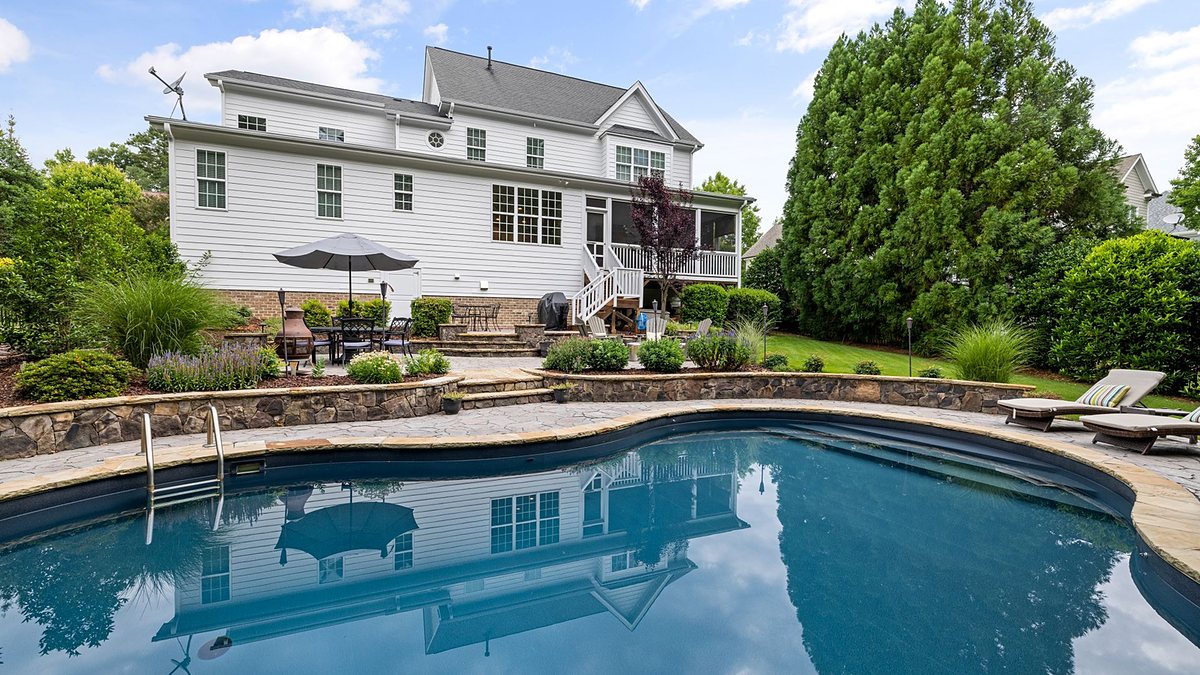White suburban house with a swimming pool and landscaped garden in a quiet neighborhood