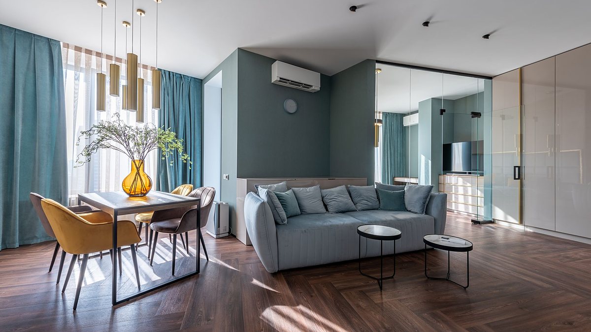 Spacious modern living room with a cozy sofa and a dining area with table, chairs and a flower vase